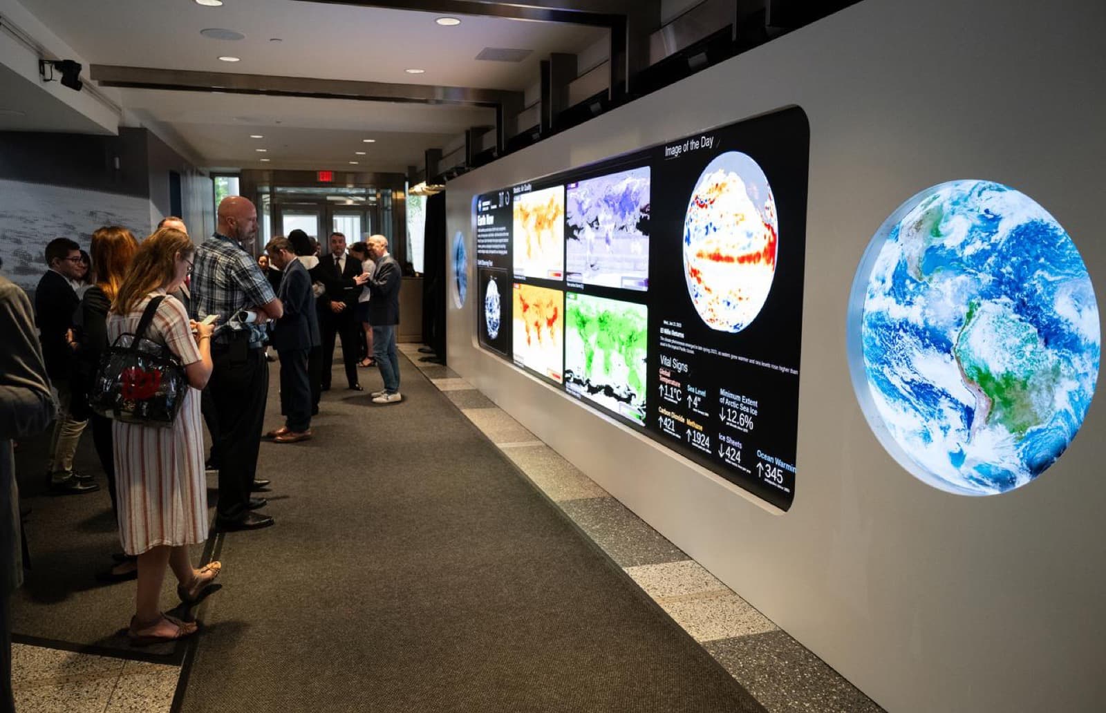 Visitantes frente al muro de visualizacion de datos del Earth Information Center de la NASA